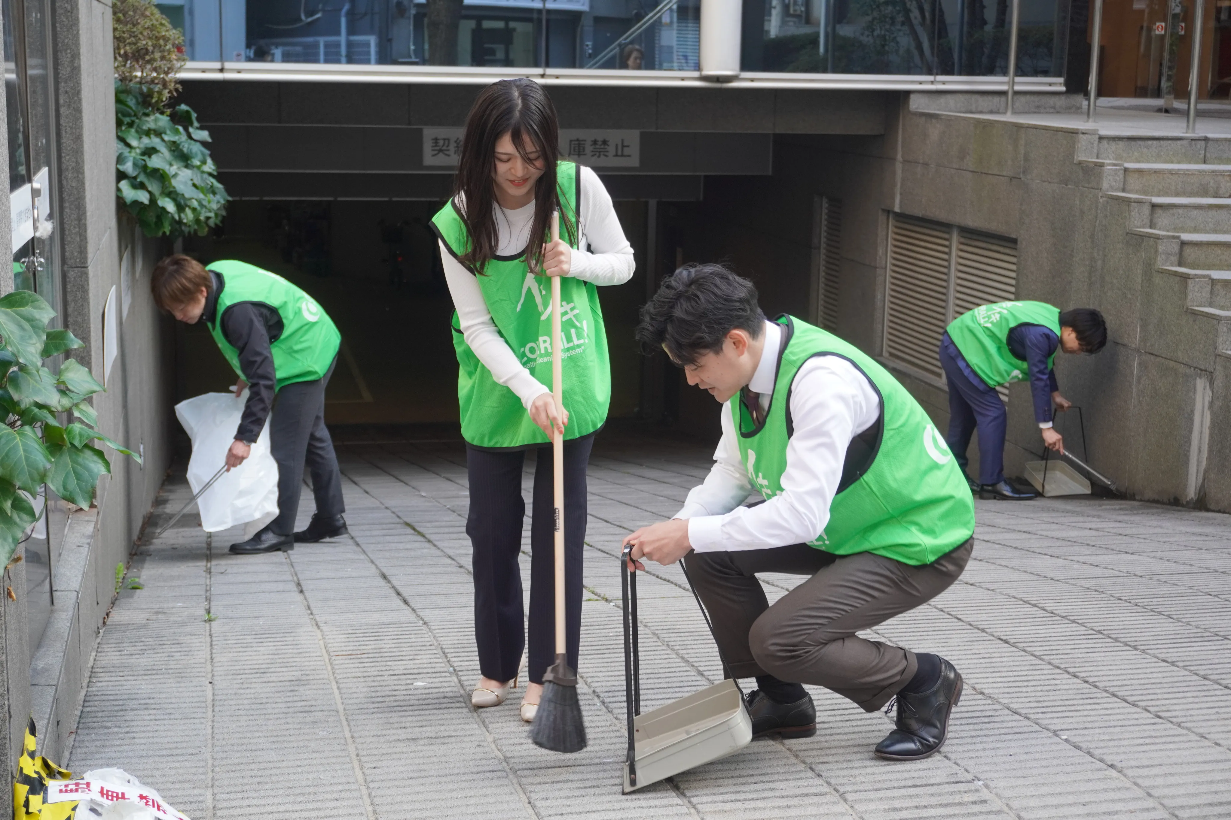 ビブスを着用したスタッフが道路を掃除している様子